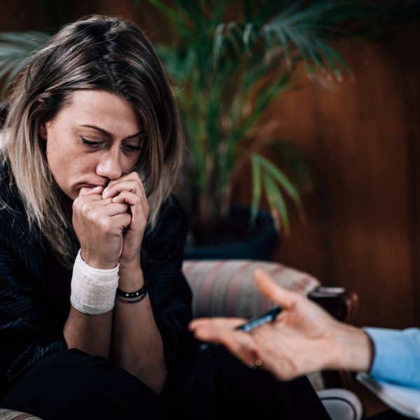 Talking therapy. Depressed woman in psychotherapy session, talking to psychotherapist, biting fingernails